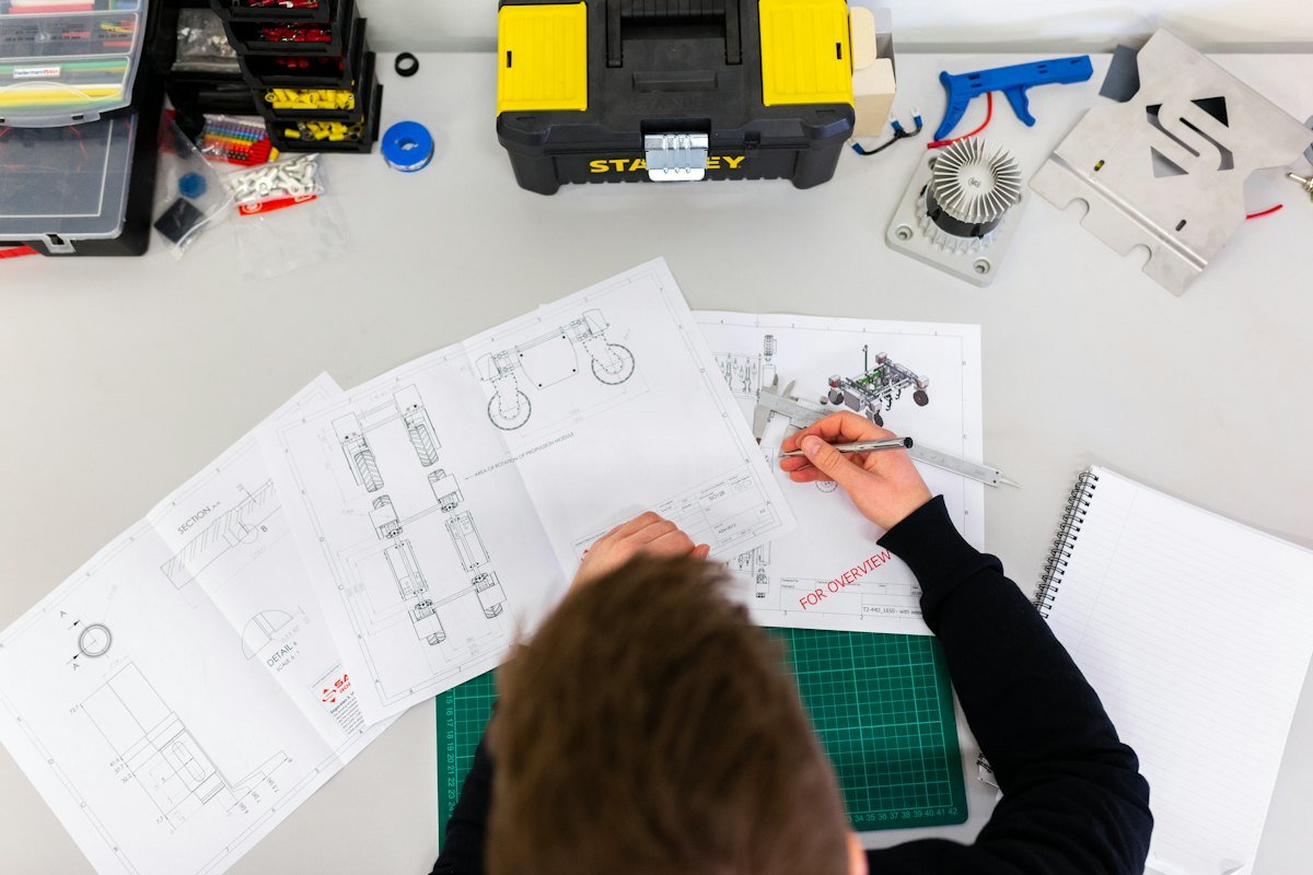 A person measuring engineering drawings with a caliper
